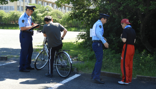 制服を着た生徒が自転車に乗った市民役に対応している様子