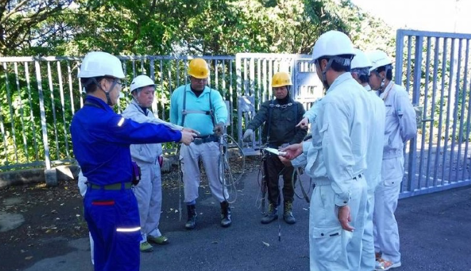 屋外で職員と作業員6名が作業予定の確認をしている様子