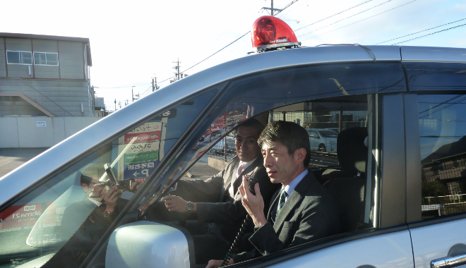 回転灯をつけた車に乗る２名の警察官の写真